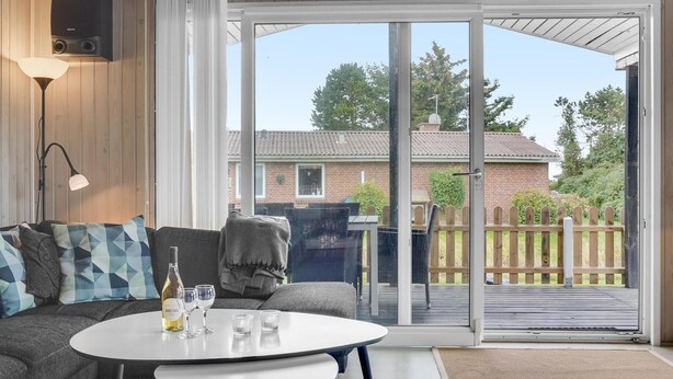 Un salon moderne avec un canapé, une table basse et une porte-fenêtre coulissante donnant sur une terrasse.