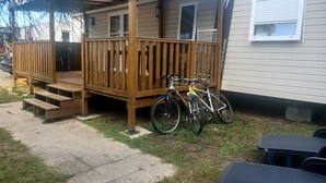 Een stacaravan met een houten terras, twee fietsen en een klein voortuintje.