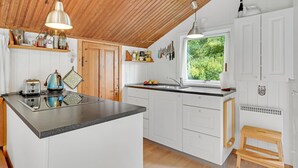 A kitchen with a wooden ceiling, white cabinets, a granite countertop, and a window with a view of greenery. - 1 bedroom awesome home in Jægerspris (Jægerspris)