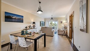 Amplia sala de estar con una mesa de comedor, sillas, un sofá y un balcón.