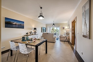 Ein großzügiger Wohnbereich mit Esstisch, Stühlen, einer Couch und einem Balkon.