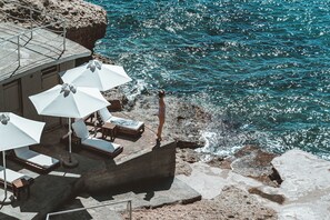 A seaside terrace with lounge chairs and umbrellas, overlooking the ocean. - Apollo Resort (Aegina)