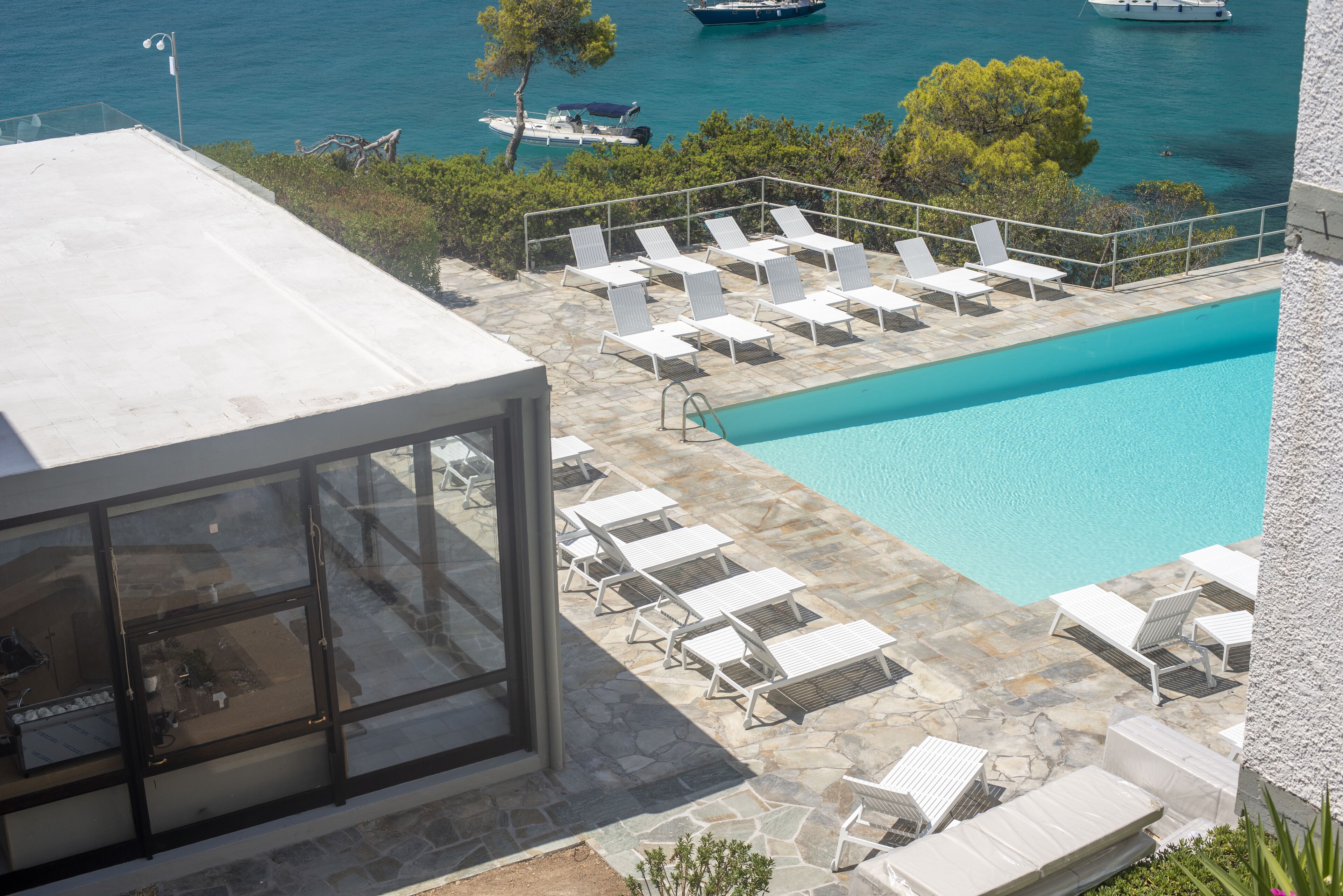 A pool area with lounge chairs and a clear view of the sea.