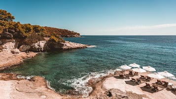 På stranden, svart sandstrand, solstolar och parasoller