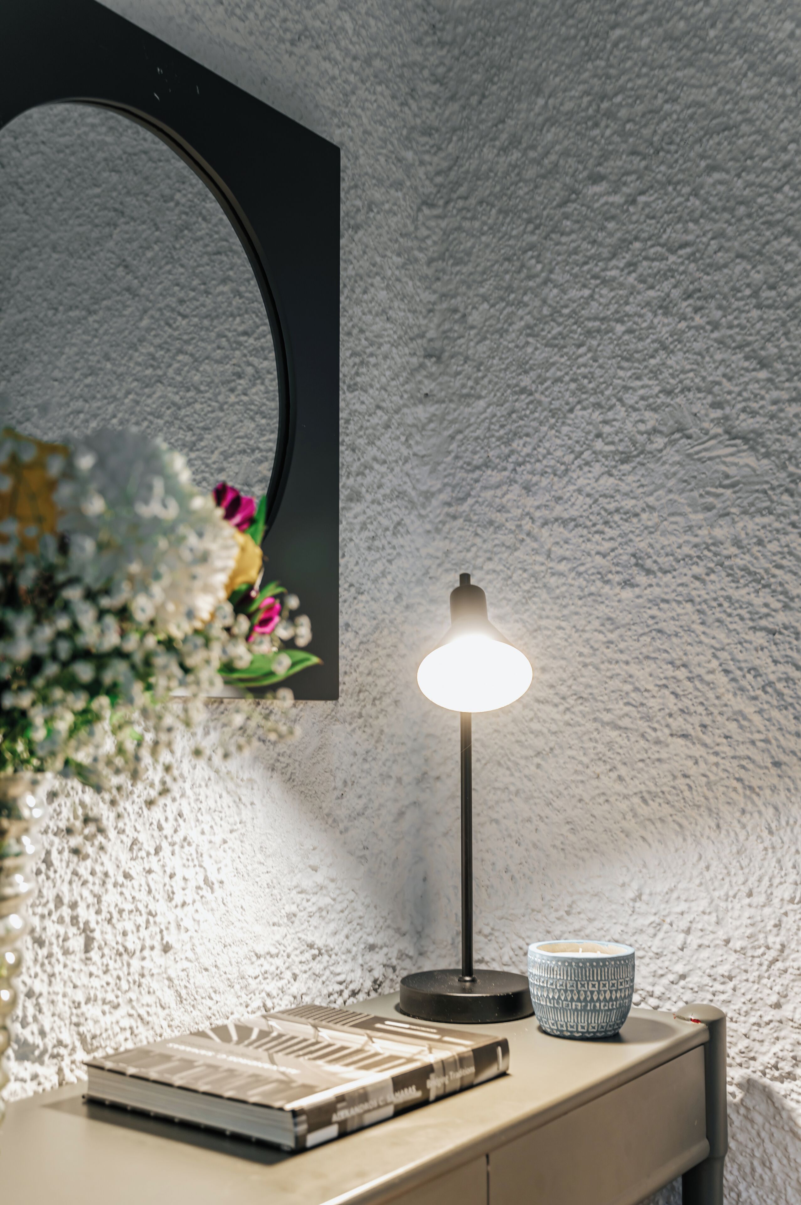 Een bureau met een lamp, een boek en een decoratieve schaal.