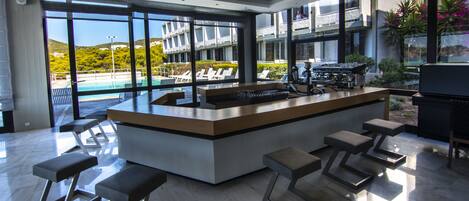 Une cuisine moderne dotée d’un îlot central, de tabourets de bar et offrant une vue sur une piscine et des montagnes.