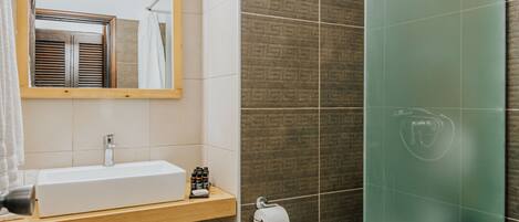 A bathroom with a wooden vanity, a mirror, a toilet, and a glass shower enclosure.