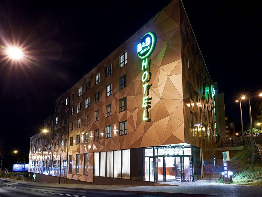 A hotel with a geometric facade and illuminated signage.
