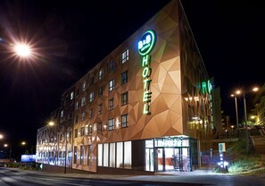 A hotel with a geometric facade and illuminated signage. - B&B Hotel Lublin Centrum (Lublin)