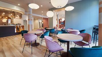 A modern interior with round tables and chairs, a reception area, and a bar.