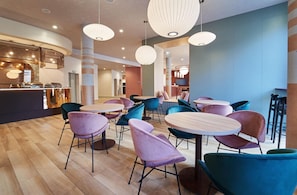 A modern interior with round tables and chairs, a reception area, and a bar. - B&B Hotel Lublin Centrum (Lublin)
