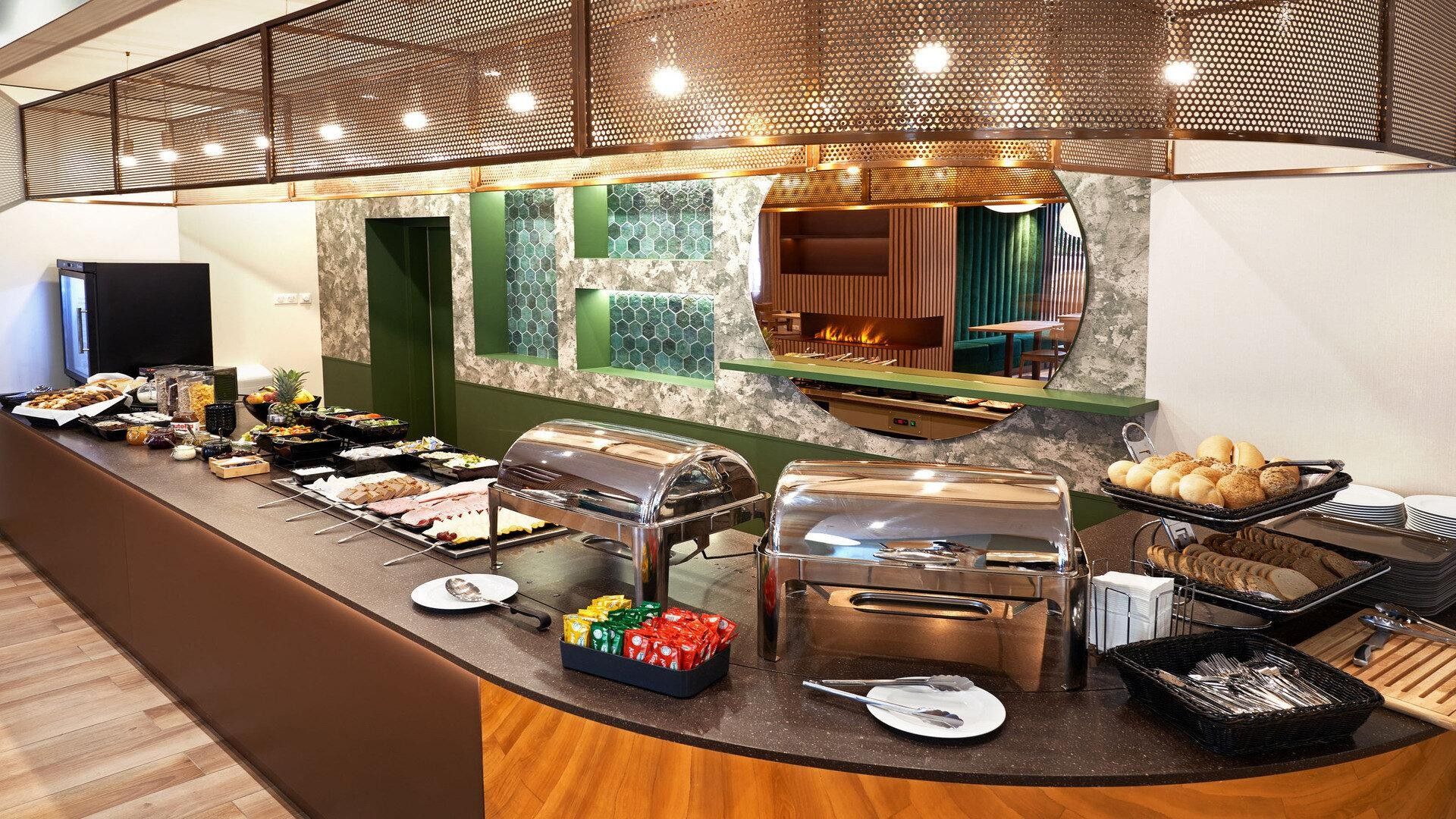 Montaje tipo buffet con diferentes opciones de comida, una estación de parrilla y una zona de estar con vista a una fogata.