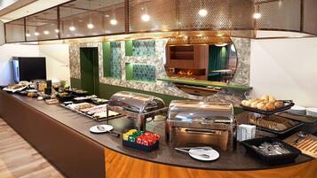Montaje tipo buffet con diferentes opciones de comida, una estación de parrilla y una zona de estar con vista a una fogata.