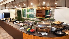 A buffet setup with various food items, a grill station, and a seating area with a view of a fire. - B&B Hotel Lublin Centrum (Lublin)