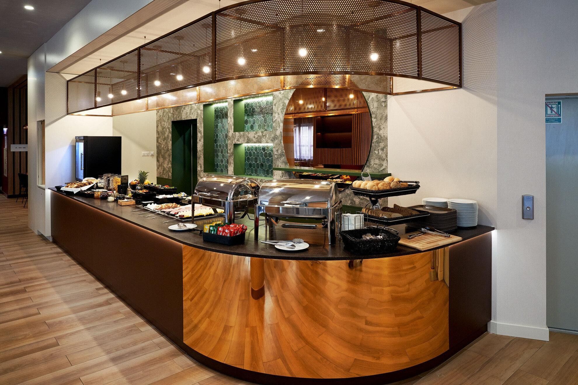 Un buffet de petit-déjeuner d’hôtel proposant une variété de plats, une machine à café et un espace détente.