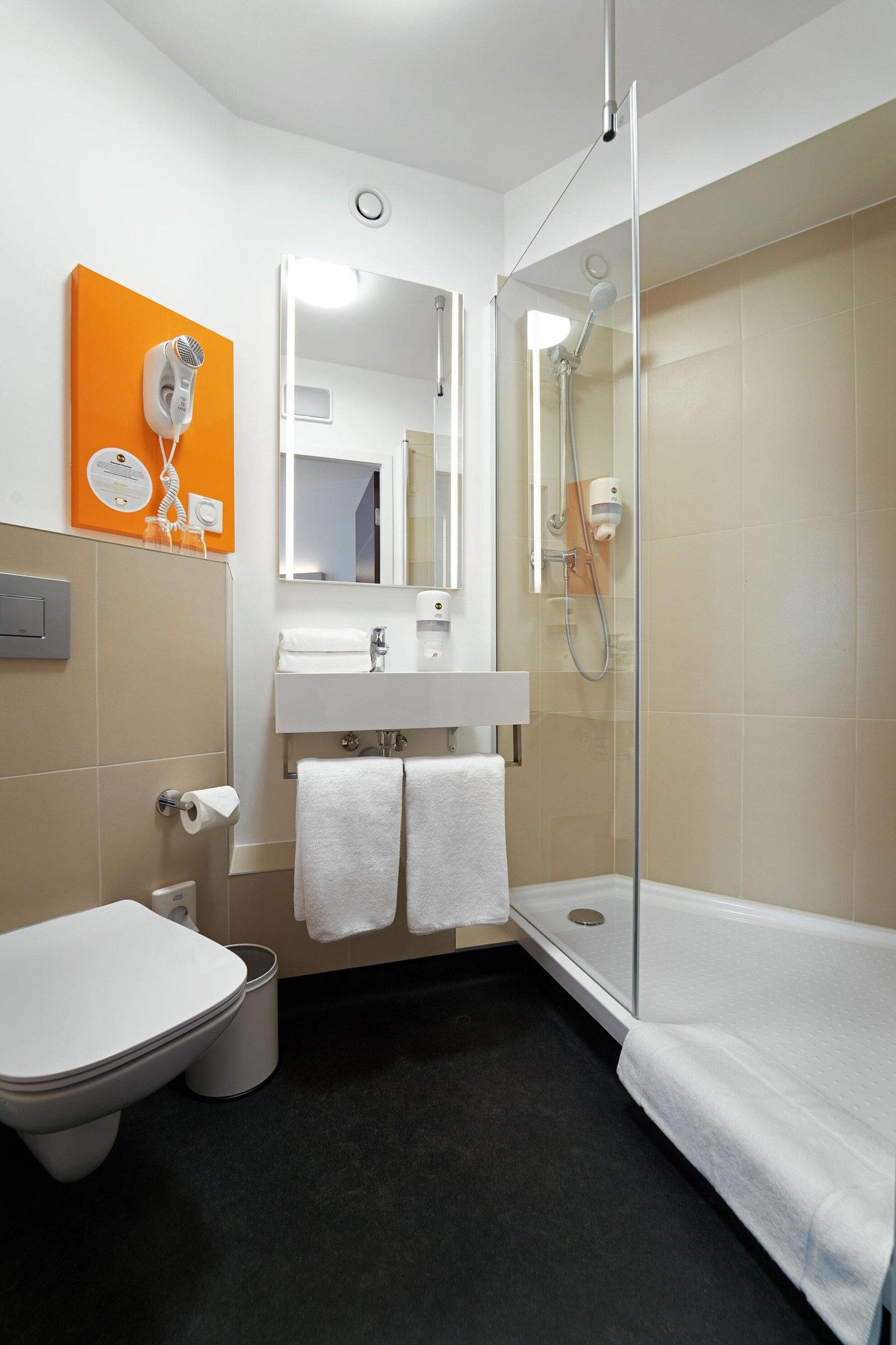 Un baño moderno con inodoro, lavamanos y ducha.