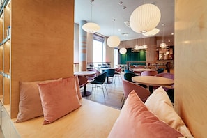 Un interior moderno con mesas y sillas redondas, ventanas amplias e iluminación decorativa.