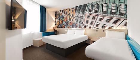 A hotel room with two beds, a large window with curtains, a wall-mounted TV, and a colorful mural.