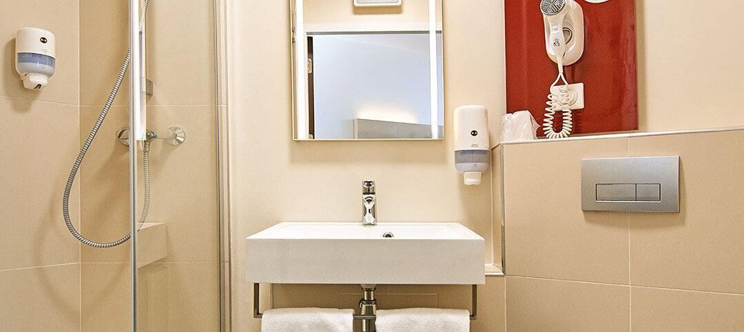 A bathroom with a shower, sink, mirror, and a hairdryer on the wall.
