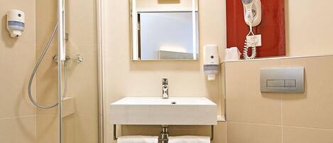 A bathroom with a shower, sink, mirror, and a hairdryer on the wall.