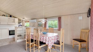 A cozy kitchen with wooden cabinets, a stove, and a dining area with a round table and four chairs. - Stunning home in Hemmet with WiFi (Hemmet)