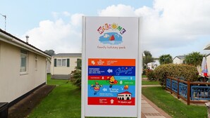 Une enseigne pour un parc de loisirs familial offrant des commodités telles qu’un centre commercial, un café, un club pour enfants, des jeux d’arcade, un bar, une discothèque, une piscine, une aire de jeux, une laverie, un terrain de sport, des piscines intérieures, une piscine intérieure pour sports, un service de location, un parcours de mini-golf et une villa de style espagnol.