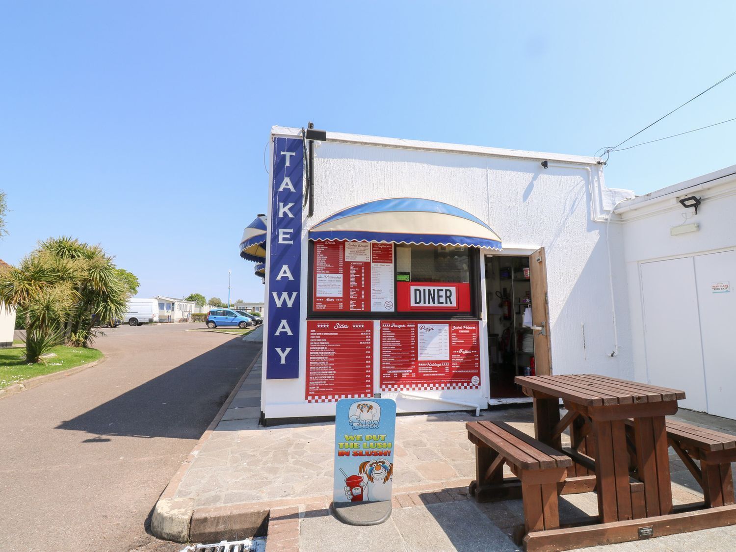 A small diner with a blue awning and a menu board outside.