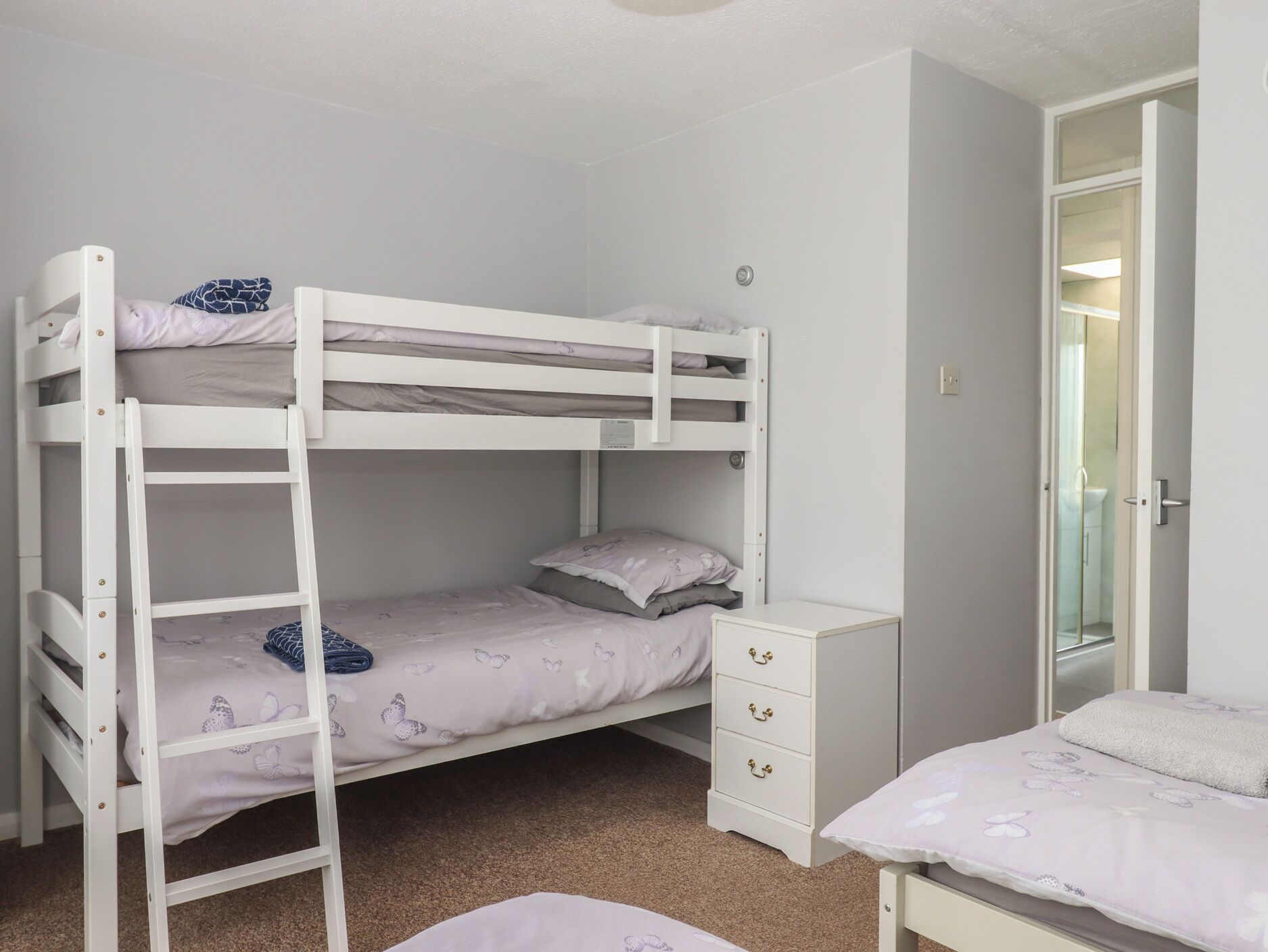 Une chambre avec un lit superposé, un bureau et un petit placard.