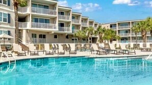 A hotel with a pool area, multiple balconies, and palm trees. - Atlantic Sunrise ~ Oceanfront, Beachfront, Pools (Tybee Island)