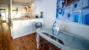 A modern kitchen with white cabinets, stainless steel appliances, and a dining area with a glass table and chairs. - Atlantic Sunrise ~ Oceanfront, Beachfront, Pools (Tybee Island)