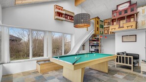 Een moderne biljarttafel binnenshuis met een groene viltbekleding, omringd door een zwart-wit betegelde vloer.