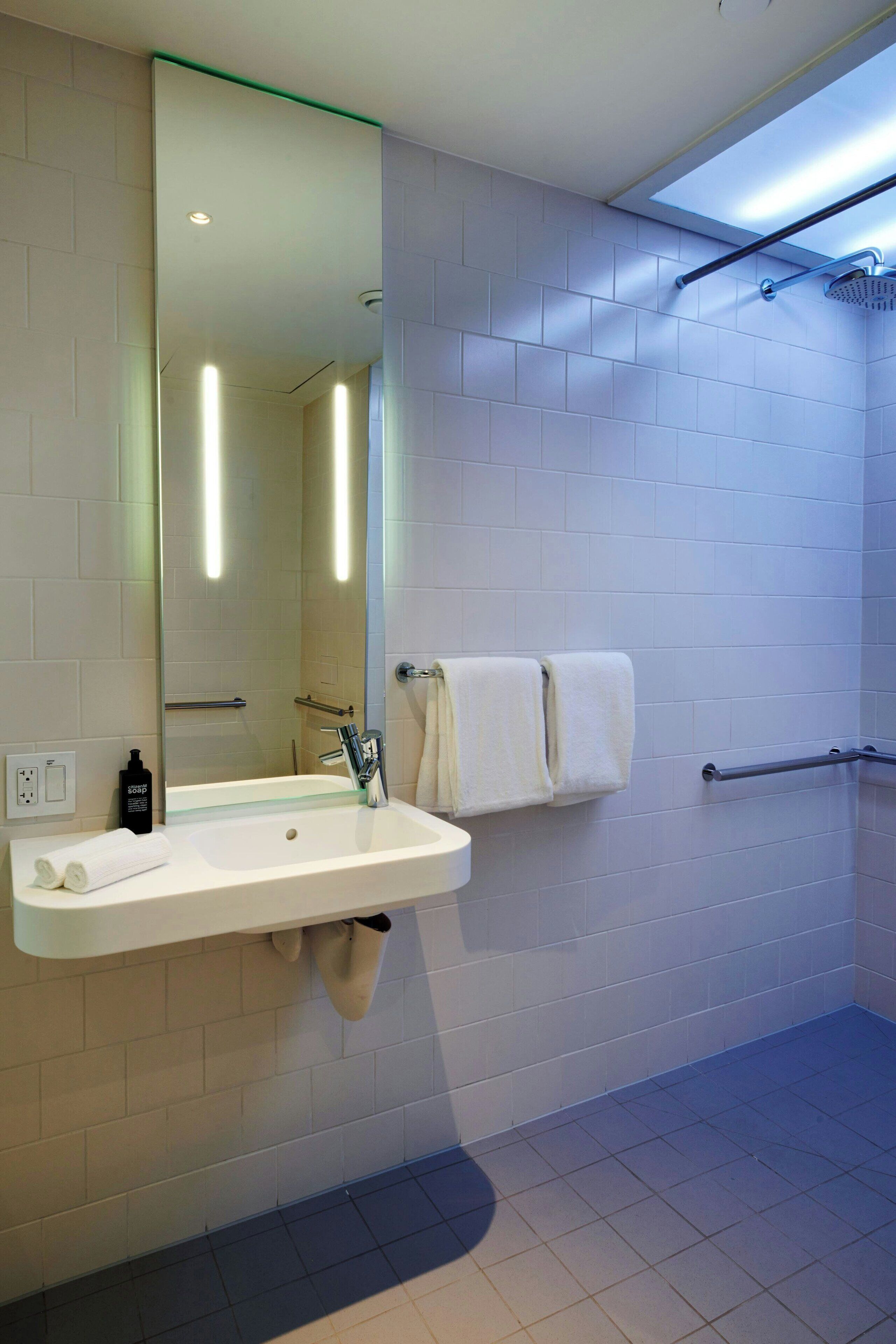 A modern bathroom with a white sink, mirror, and shower.