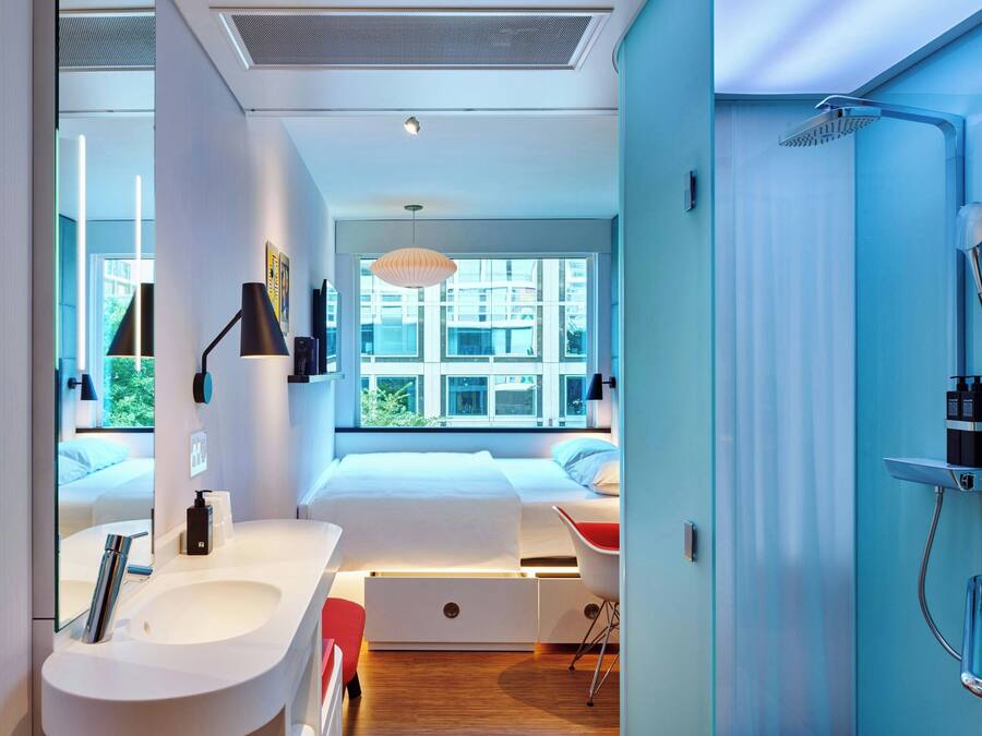 A modern bathroom with a shower, a sink, and a mirror. There is a window providing natural light and a view of the outside.