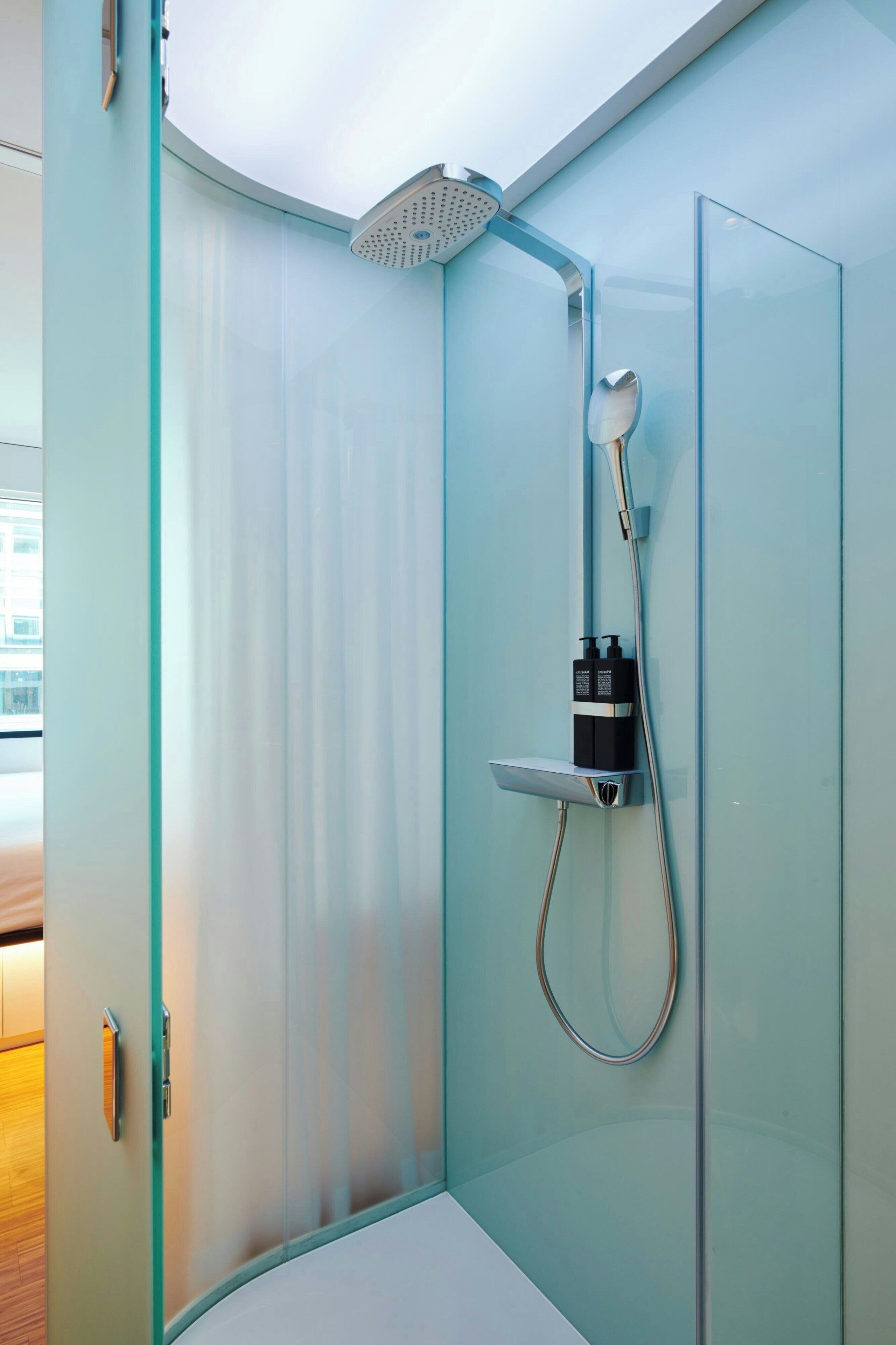 A modern shower with a glass enclosure, a handheld showerhead, and a wall-mounted faucet.