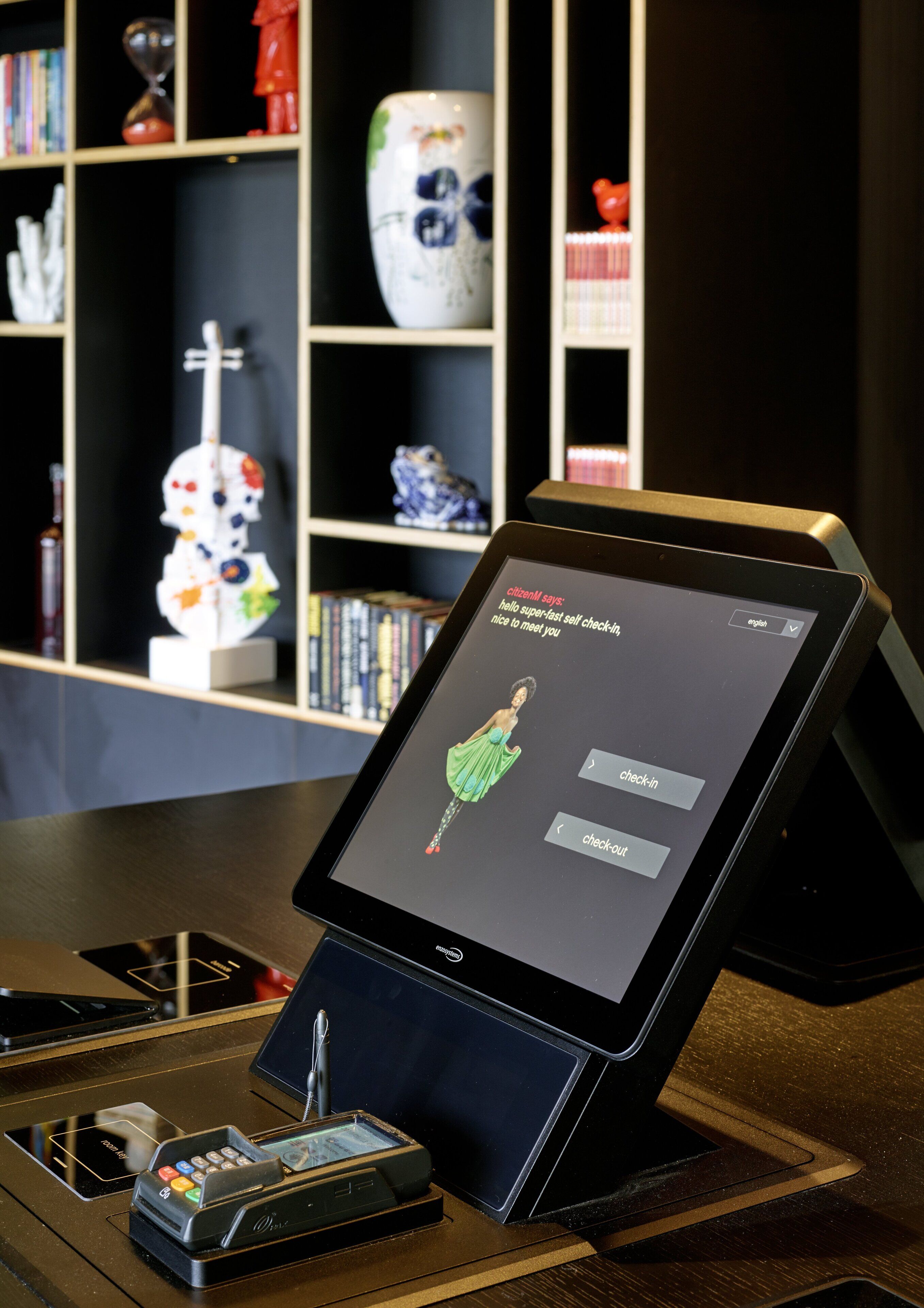 Un quiosco de auto-registro con una pantalla digital que muestra un mensaje de bienvenida y opciones para el registro y la salida.