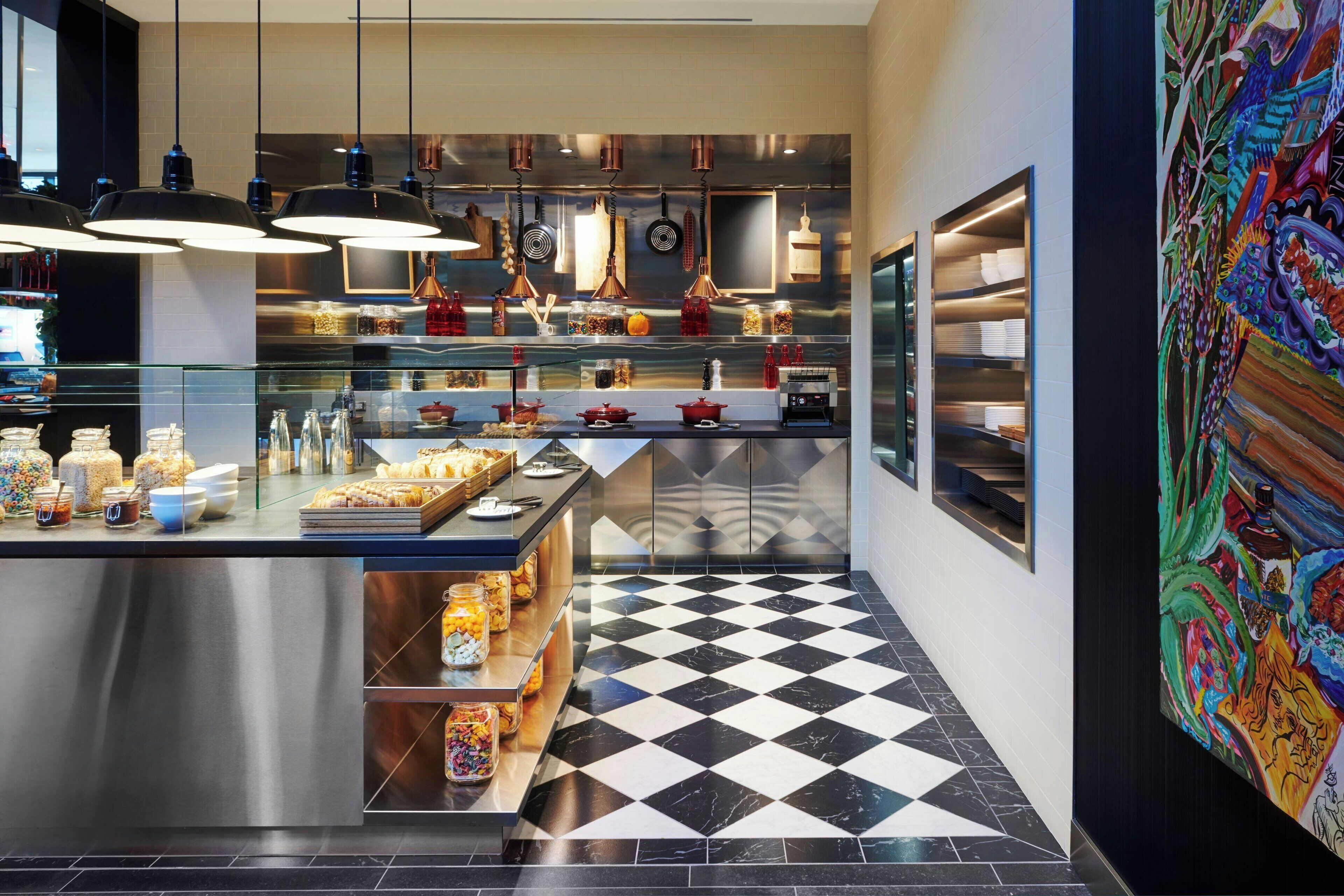A modern kitchen with stainless steel appliances, a checkered floor, and hanging pendant lights.