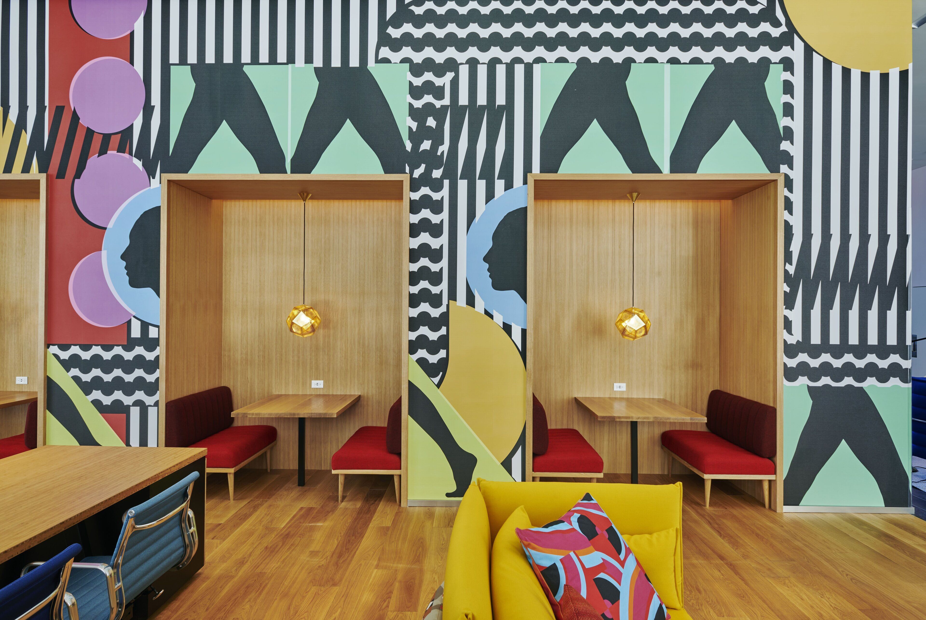 A modern interior with wooden furniture, red seating, and abstract wall art.