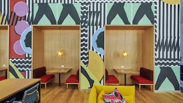 A modern interior with wooden furniture, red seating, and abstract wall art.