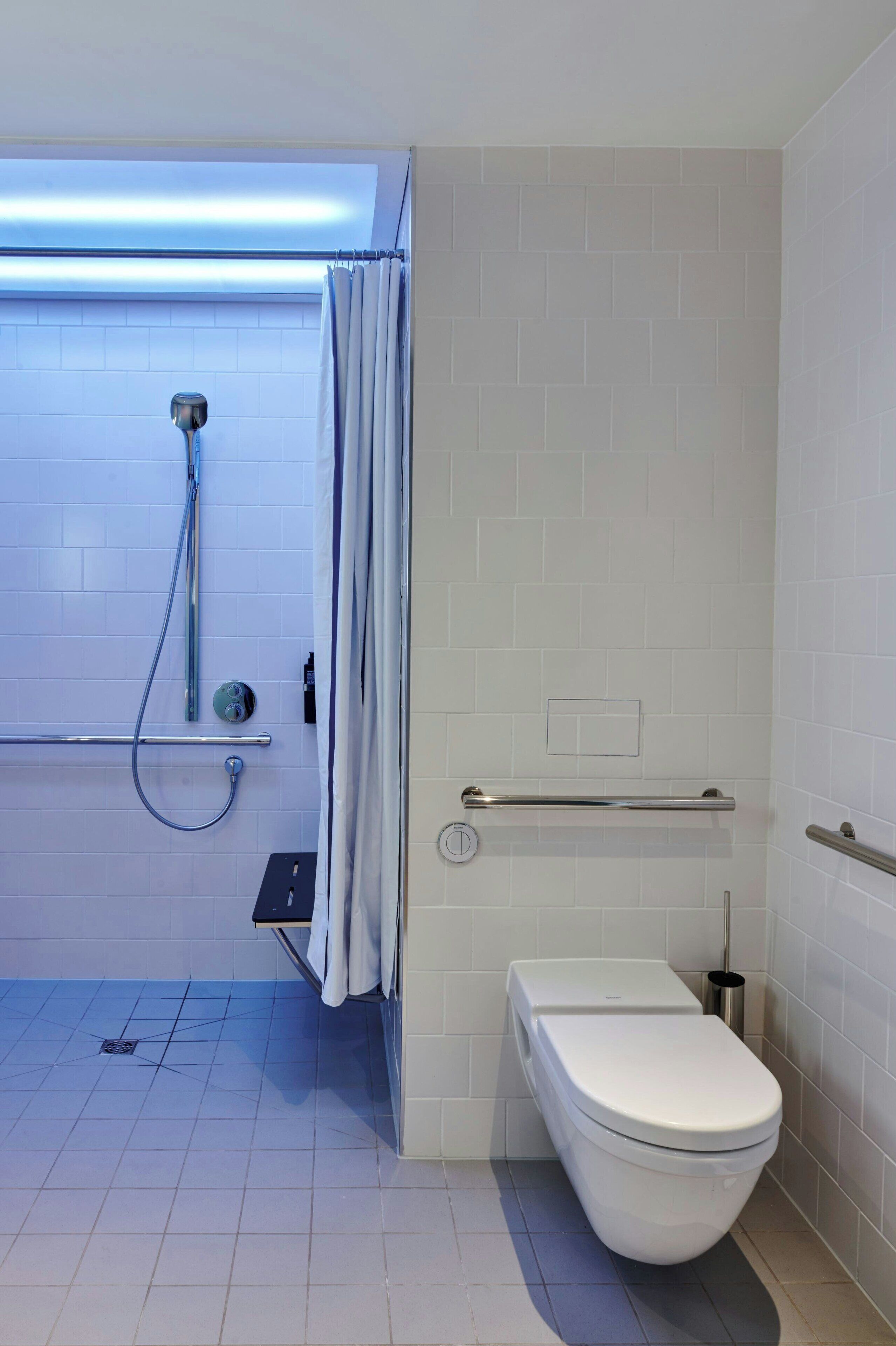 A modern bathroom with a shower, toilet, and grab bars.