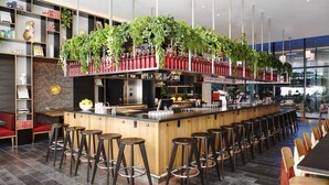 Zona de bar moderna con una isla central, taburetes y estantes con diversos objetos.