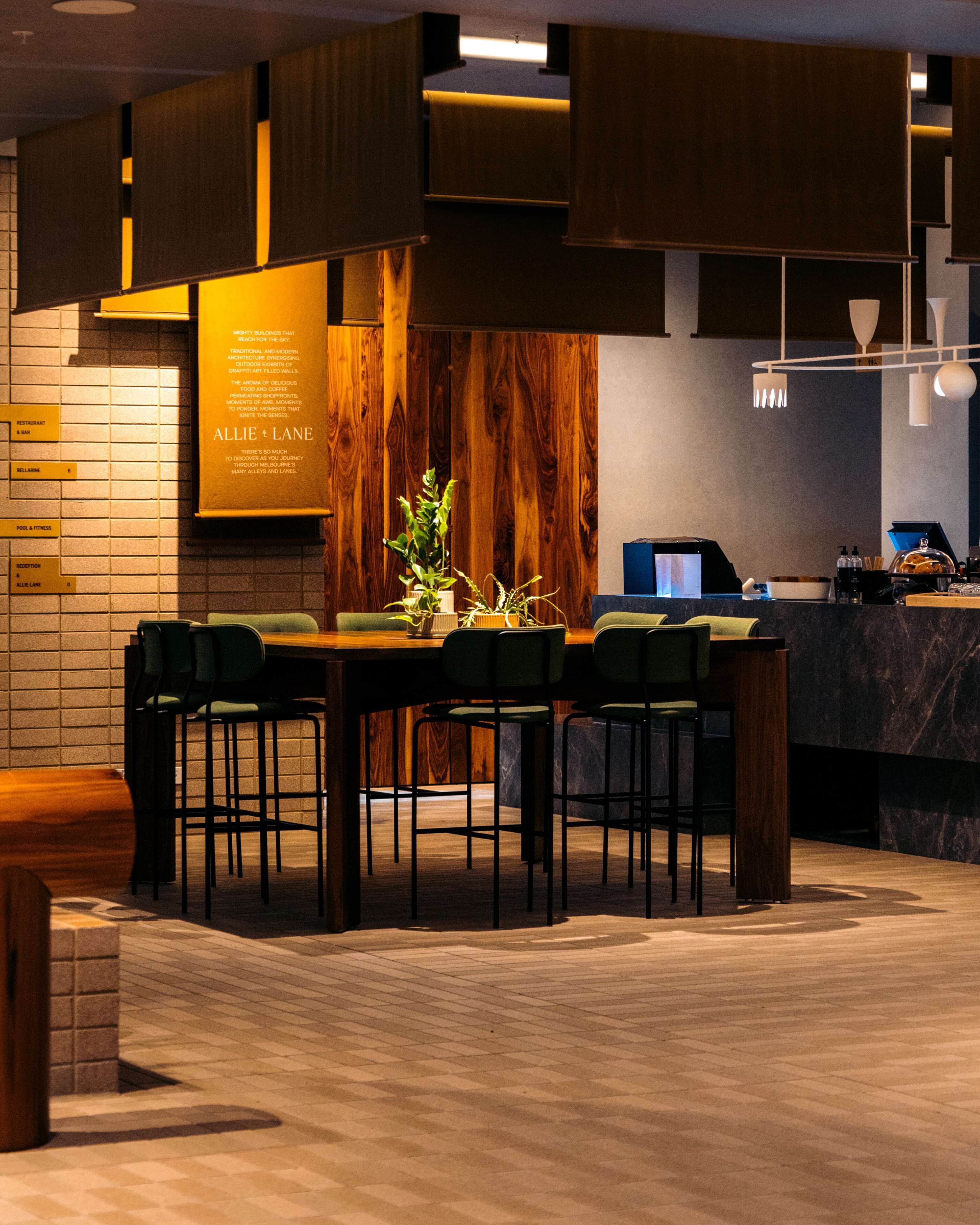Un restaurant moderne avec un mur en bois et un tableau affichant le menu. On y trouve plusieurs tables et chaises.