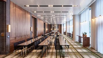 A long dining area with multiple tables and chairs, a patterned carpet, and a modern ceiling design.