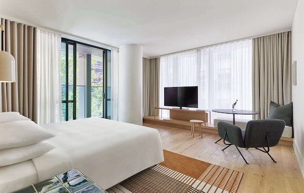 A hotel room with a large bed, a TV, a small table, and a chair.