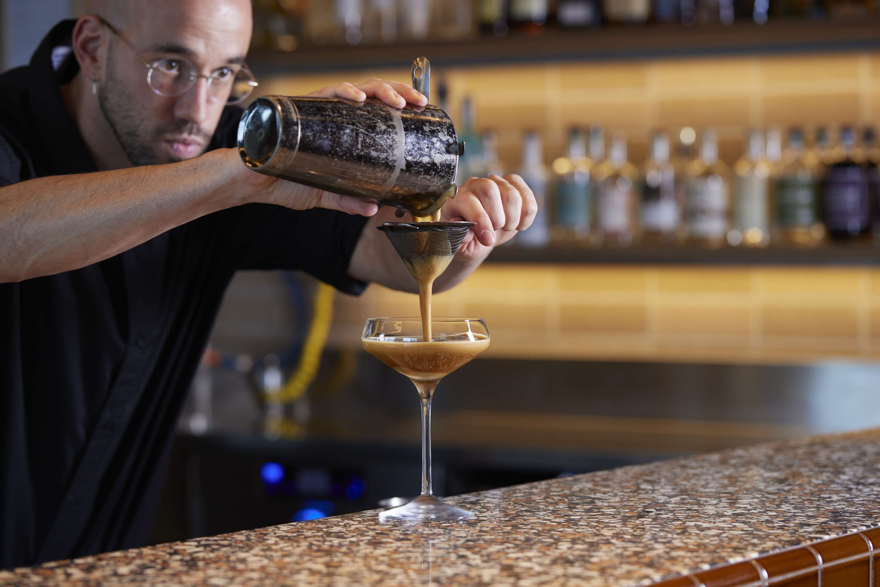 Un camarero sirviendo una bebida en una copa de martini.