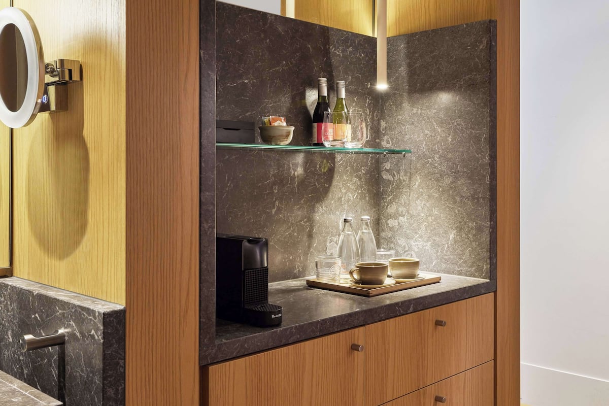 A modern kitchen with a marble countertop, wooden cabinets, and a coffee machine.