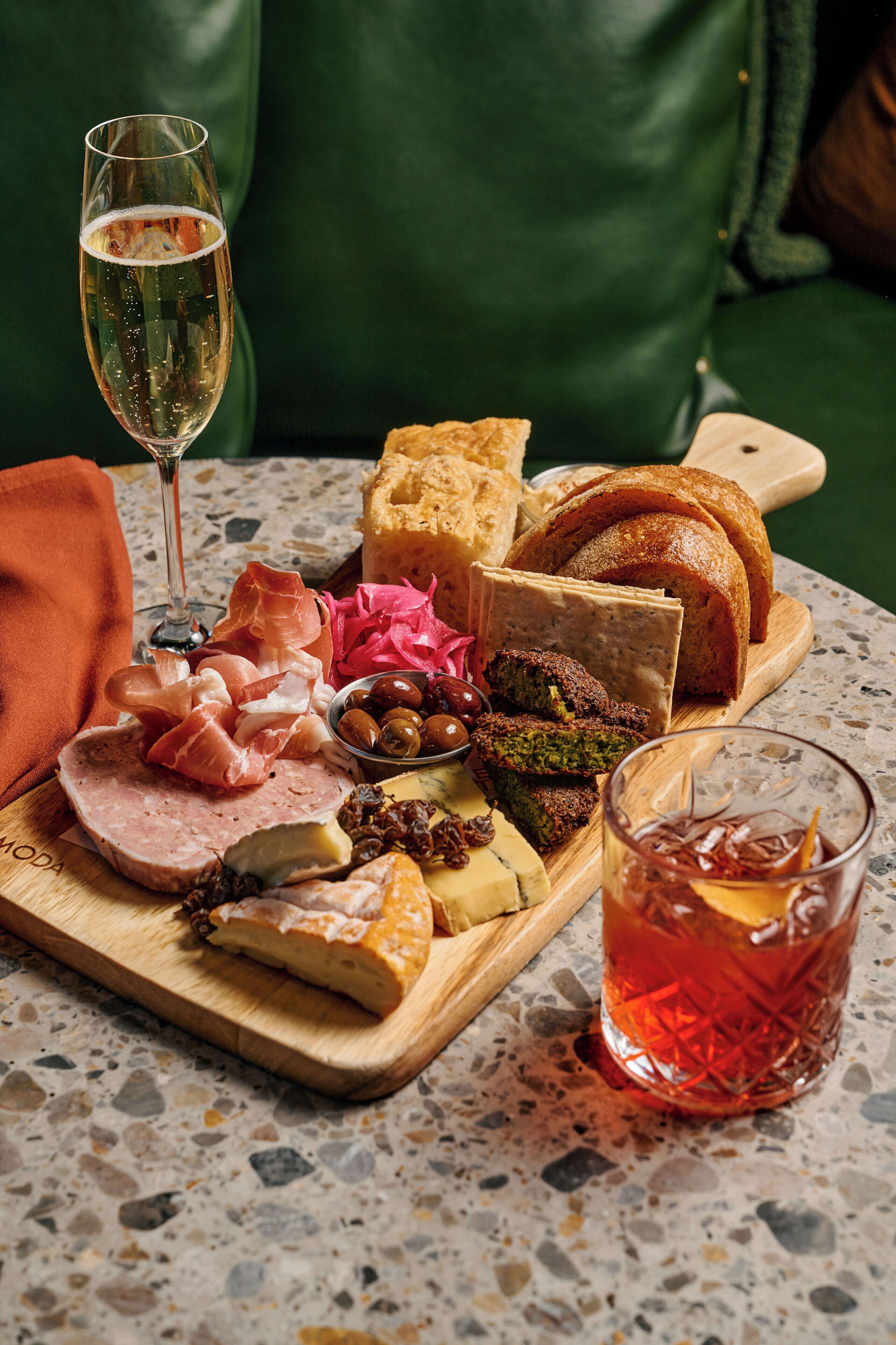 A charcuterie board with various meats, cheeses, olives, and bread on a table.