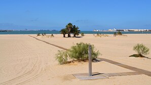 A sandy beach with palm trees and a clear blue sky. - Portus Gaditanus s XVIII Patio Andaluz (El Puerto de Santa Maria)