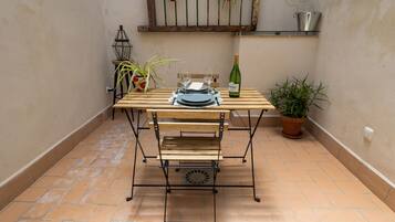 Een houten tafel met metalen frame, twee wijnglazen, een wijnfles en een placemat.