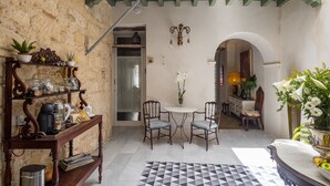 A cozy room with a wooden coffee table, two chairs, a patterned rug, and a bookshelf with decorative items. - Portus Gaditanus s XVIII Patio Andaluz (El Puerto de Santa Maria)