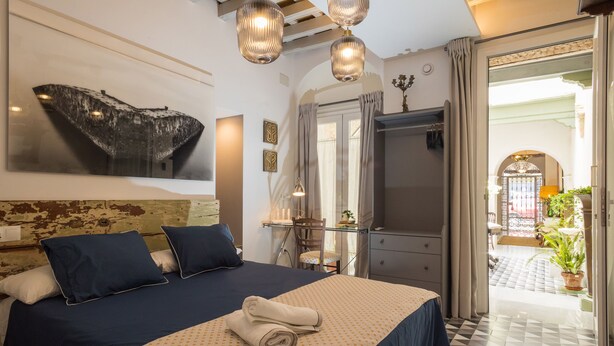 A hotel room with a large bed, a desk, and a view of the courtyard. - Portus Gaditanus s XVIII Patio Andaluz (El Puerto de Santa Maria)